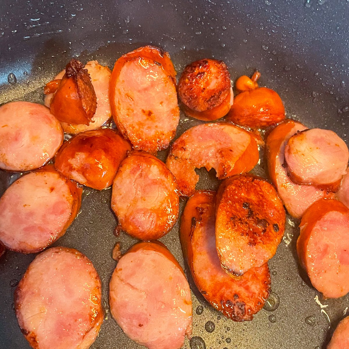 Sausage and vegetable stew cooking in a skillet with kielbasa, potatoes, courgette and peppers