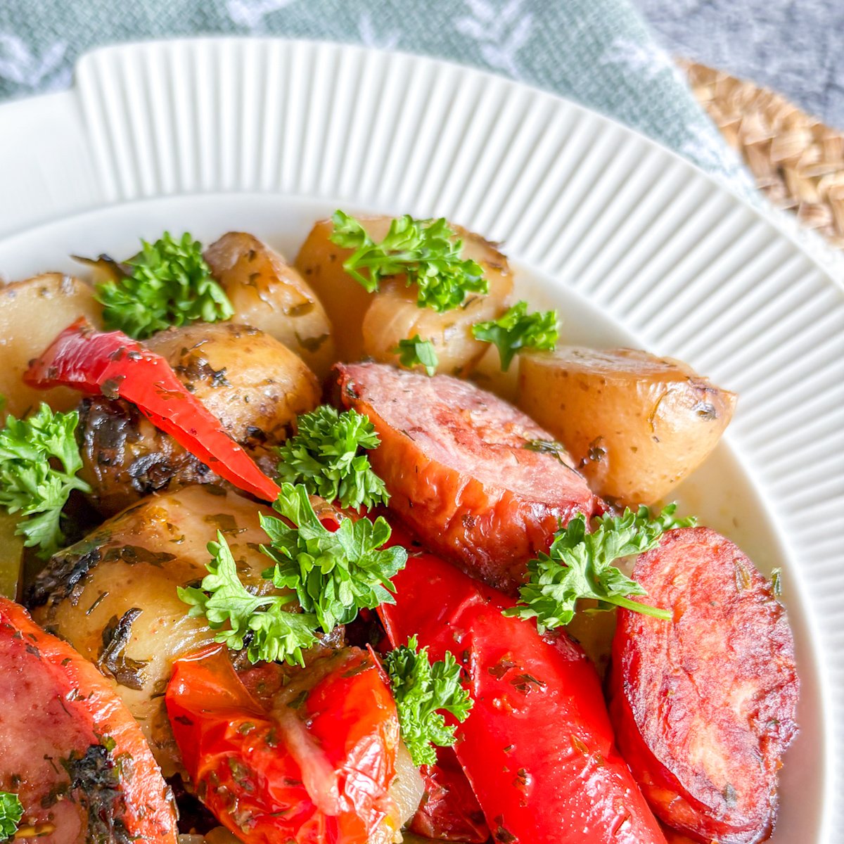 Close-up of smoked sausage stew with kielbasa, baby potatoes, peppers and burst cherry tomatoes