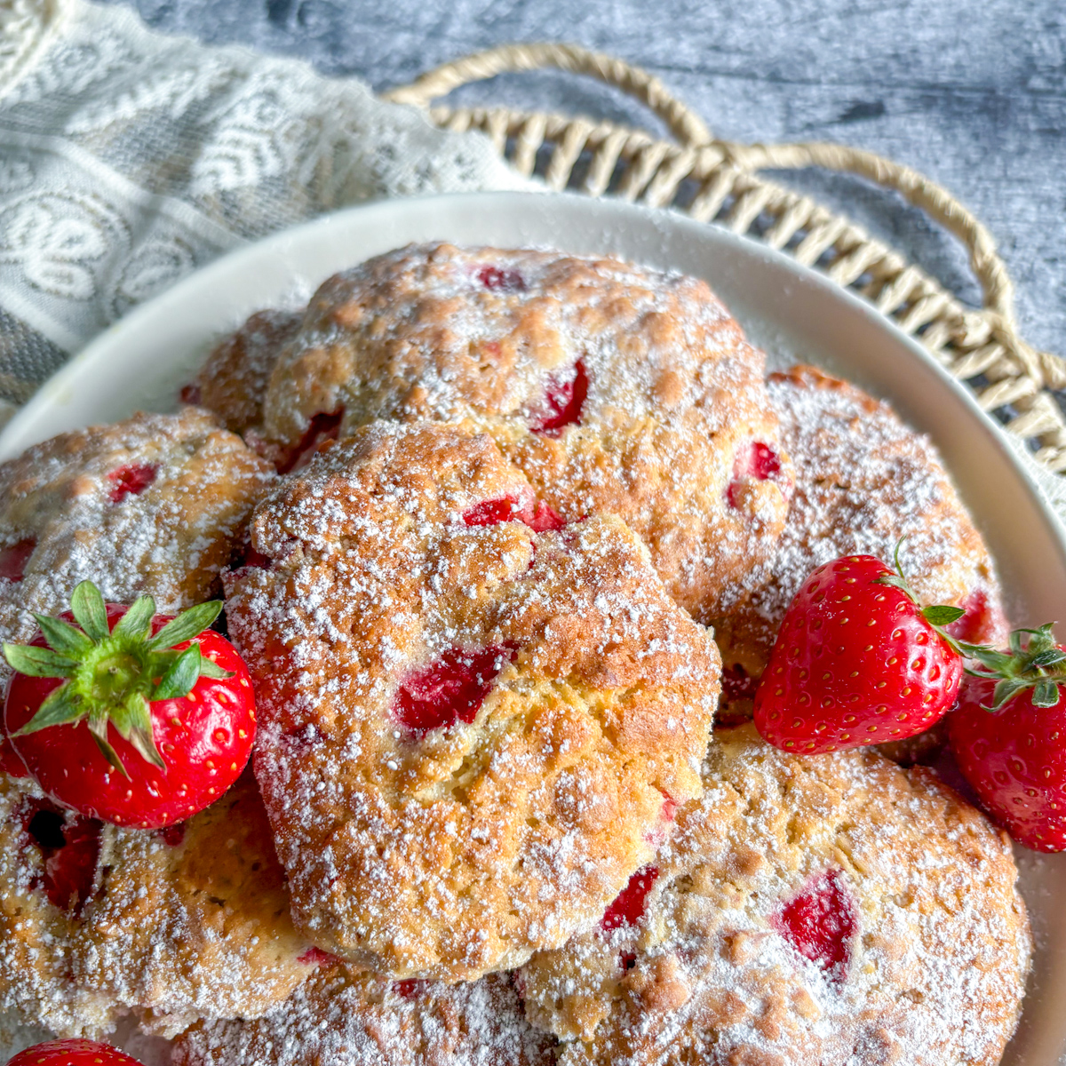 Strawberry oatmeal cookies piled on a white plate with juicy fresh strawberries