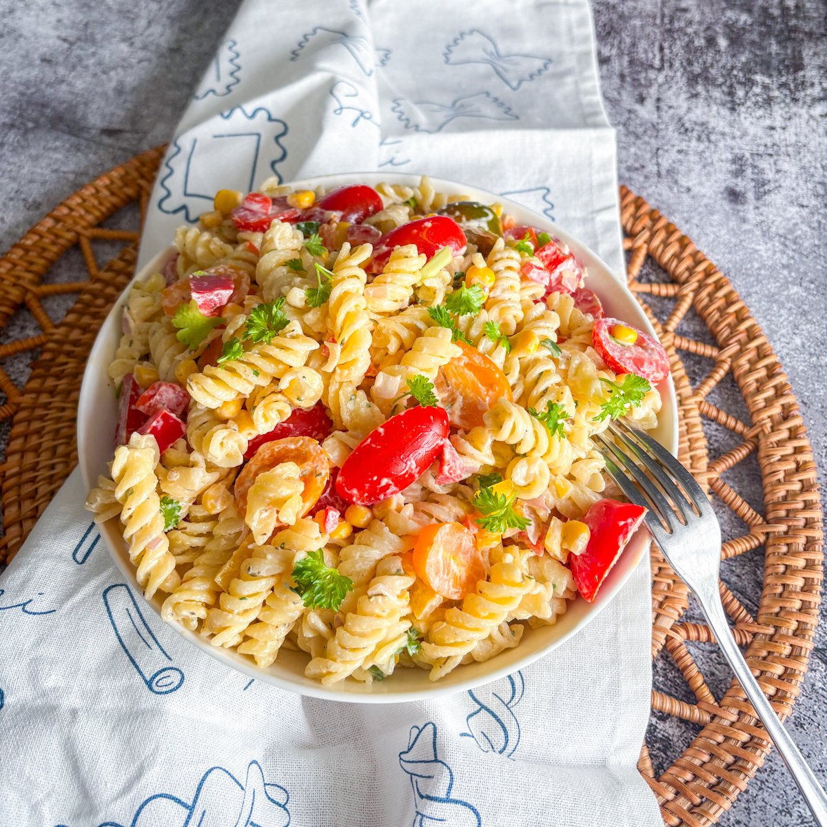 Top-down view of summer pasta salad recipe with rainbow tomatoes and fresh parsley garnish