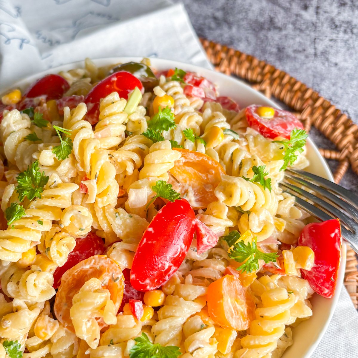 Close-up of summer pasta salad recipe showing creamy fusilli, tomatoes and fresh parsley