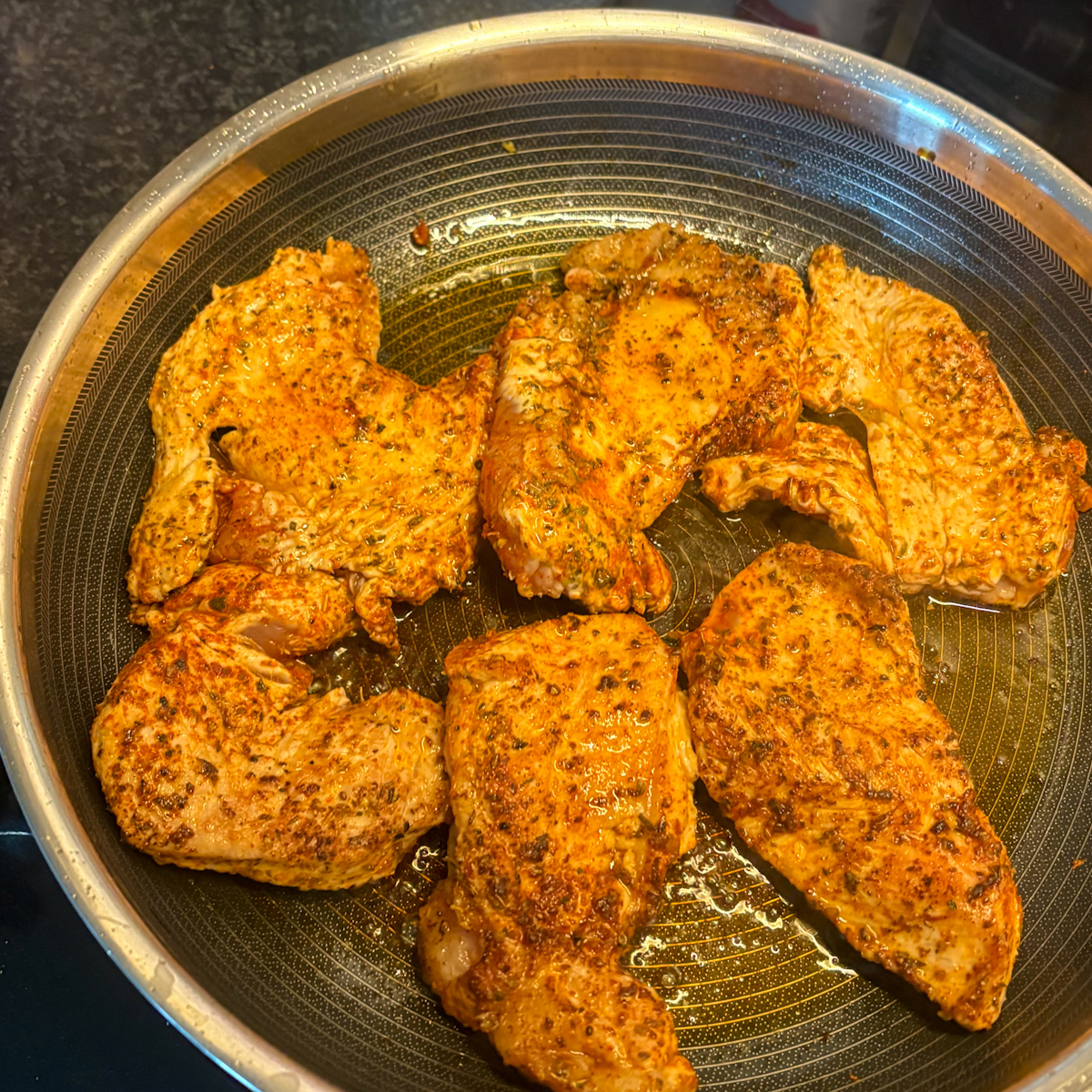 Seasoned turkey steaks pan-frying in a skillet, golden-seared on both sides