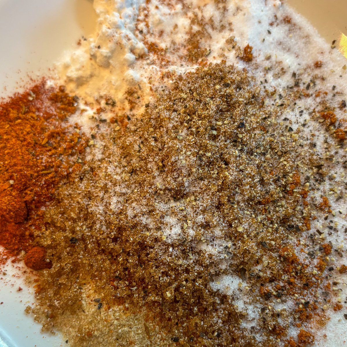 Dry rub for Guinness chicken wings in a bowl, showing smoked paprika, cayenne, salt and pepper mixed together.