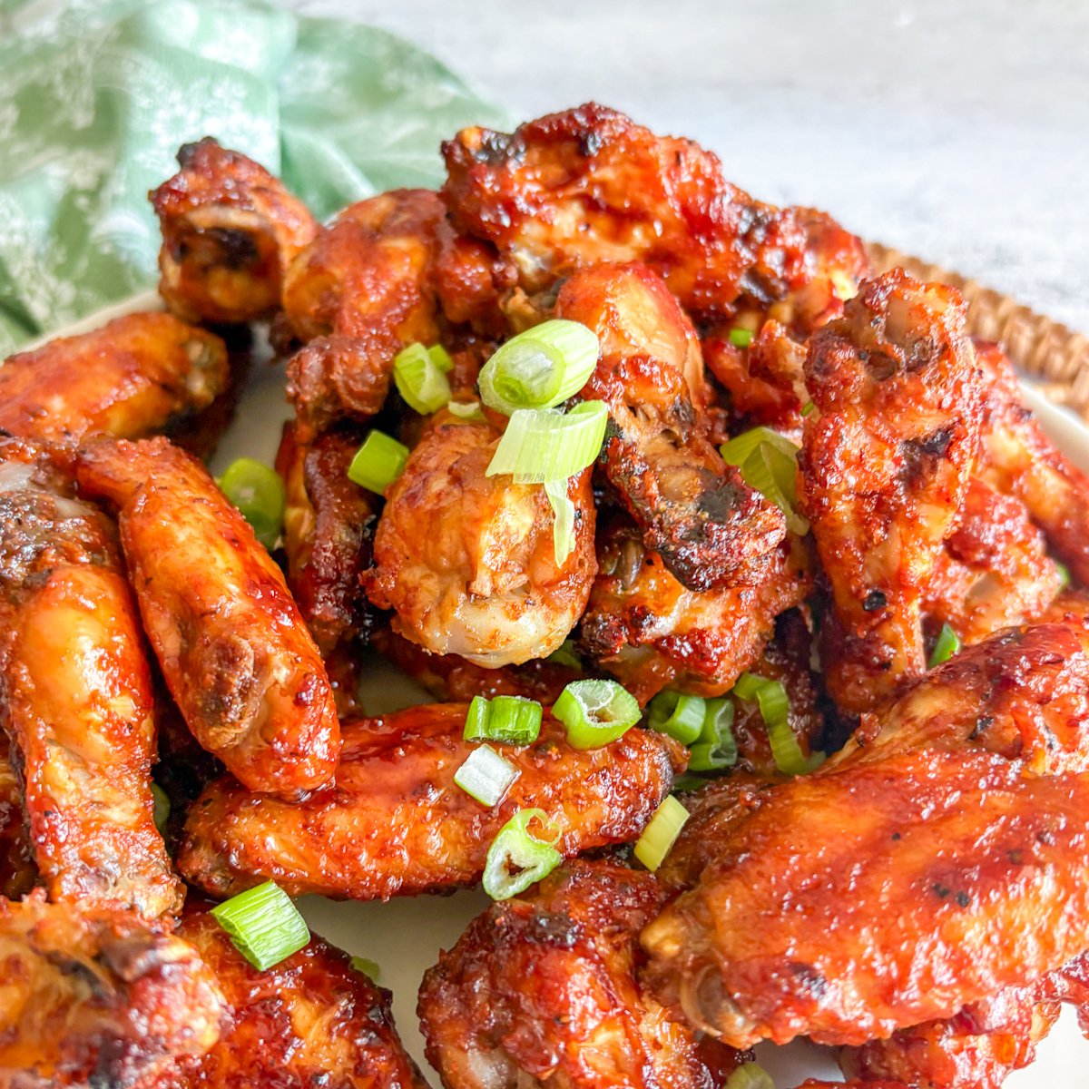 Close-up of glossy Guinness chicken wings topped with chopped spring onions, showing the caramelised stout glaze.