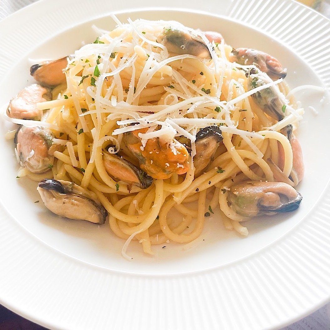 Close-up of mussel pasta recipe with spaghetti, briny mussel meat and grated parmesan tossed in a light lemon garlic sauce