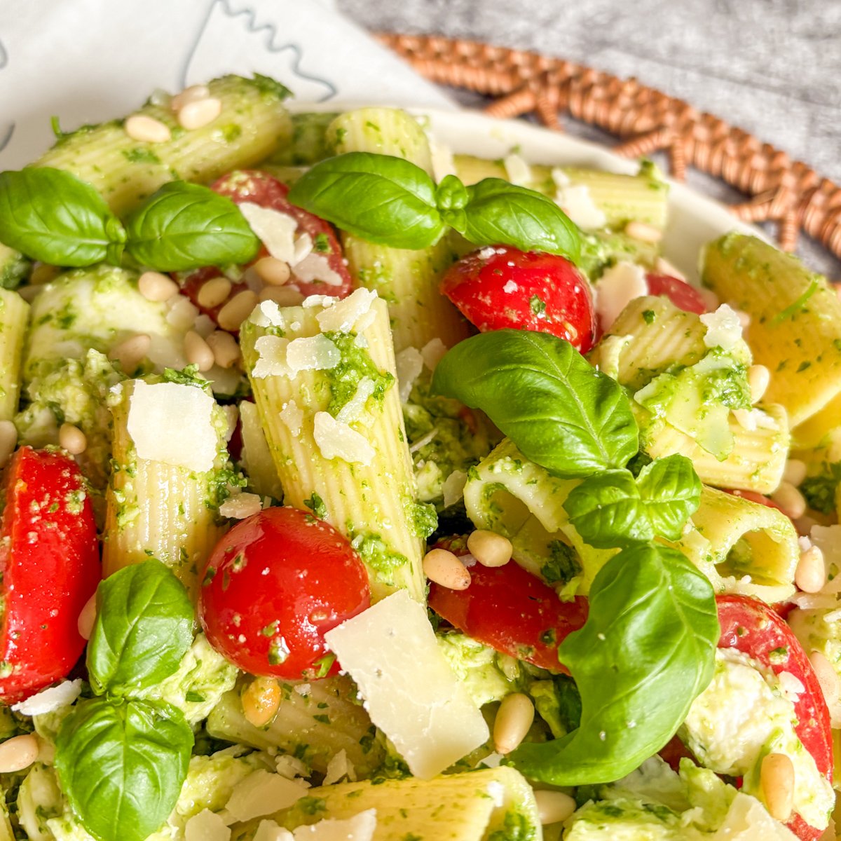 Rigatoni pesto pasta salad topped with Parmesan shavings, pine nuts and fresh basil leaves