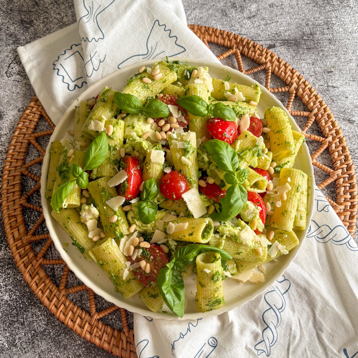 Cold pesto pasta salad with rigatoni, red tomatoes, torn mozzarella and scattered pine nuts