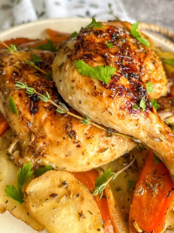 One-pan chicken legs with vegetables plated with carrots, parsnips and fresh herbs
