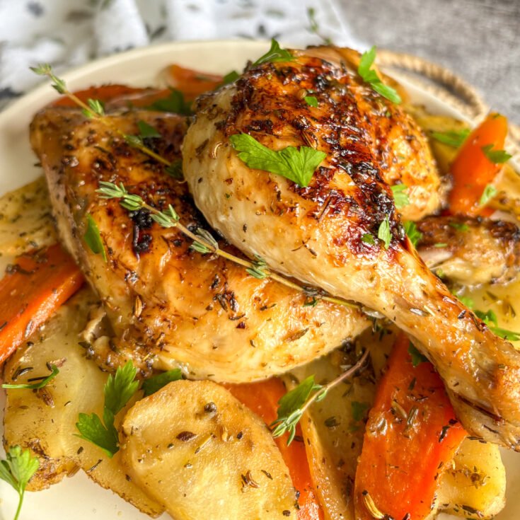 One-pan chicken legs with vegetables plated with carrots, parsnips and fresh herbs