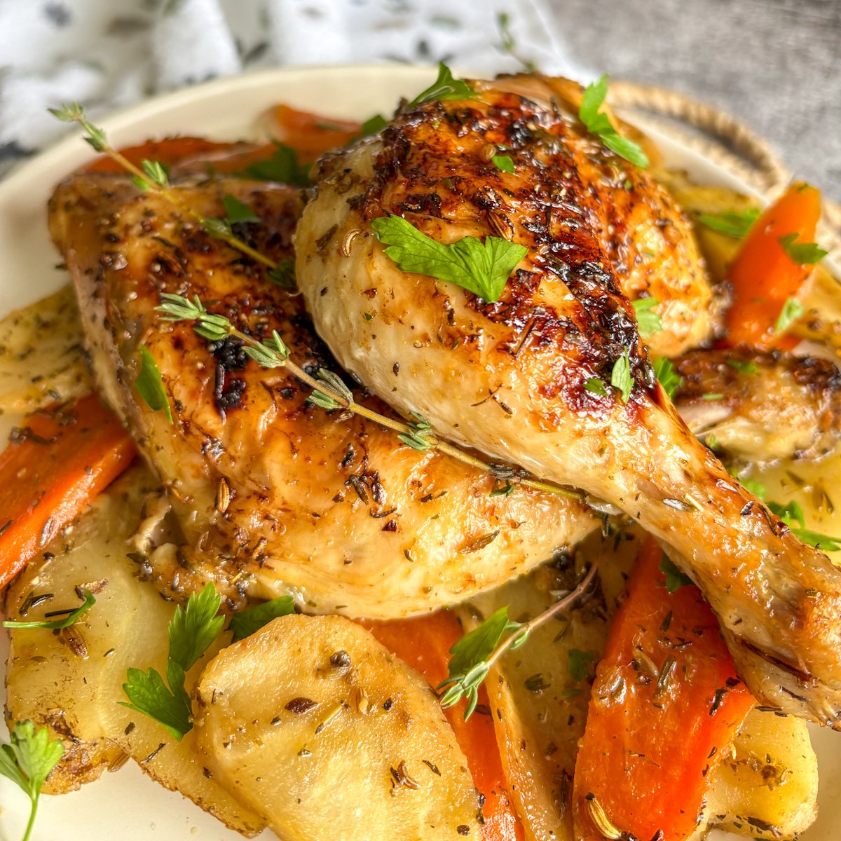 One-pan chicken legs with vegetables plated with carrots, parsnips and fresh herbs