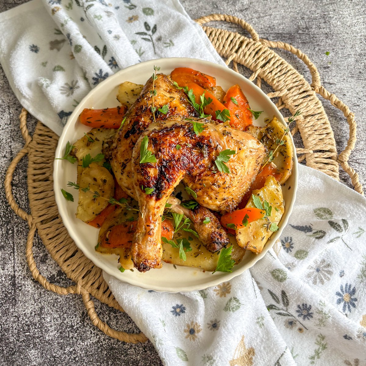 Overhead chicken legs with vegetables, carrots and potatoes on a floral napkin