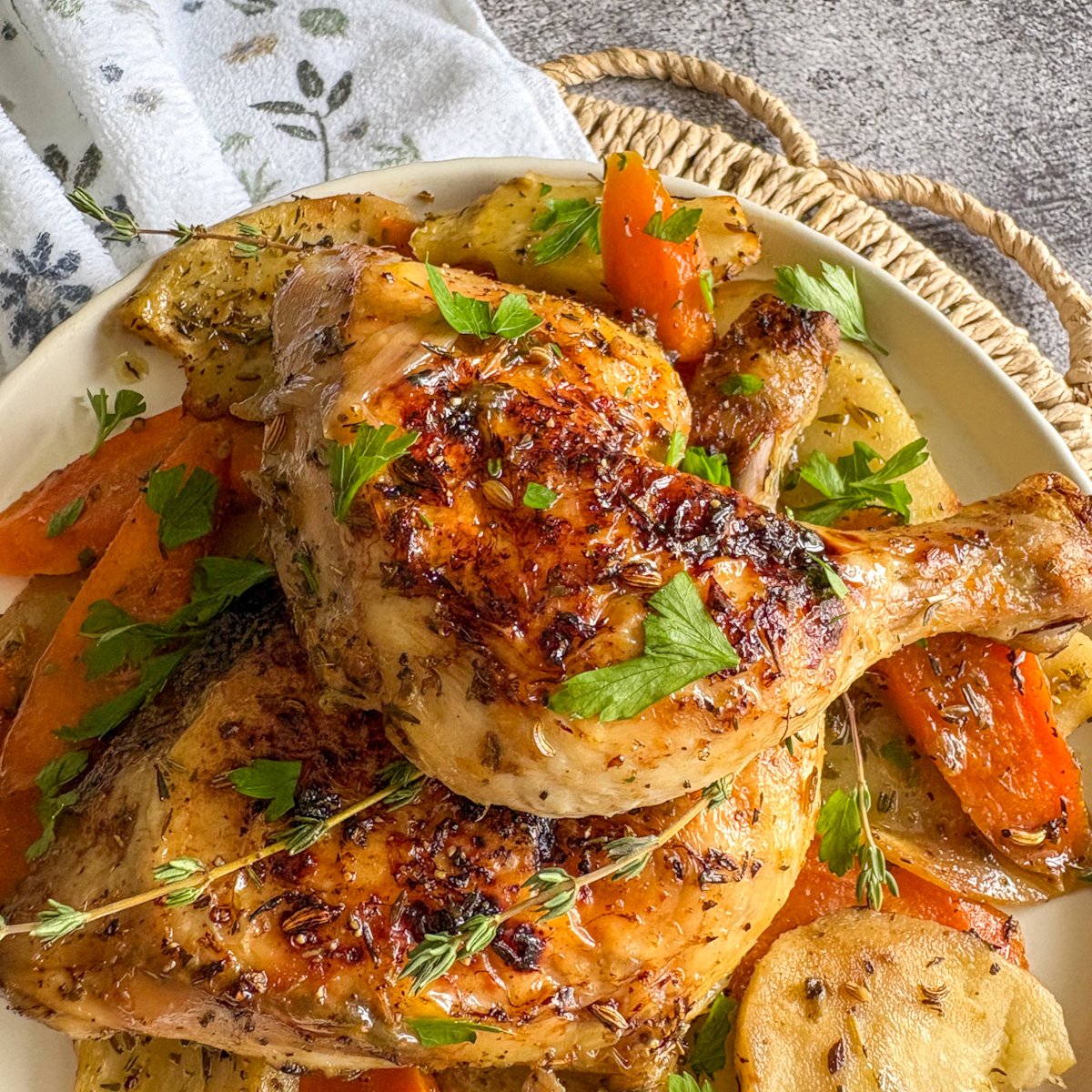 Close-up of crispy chicken legs with vegetables, carrots and herbs on a cream plate