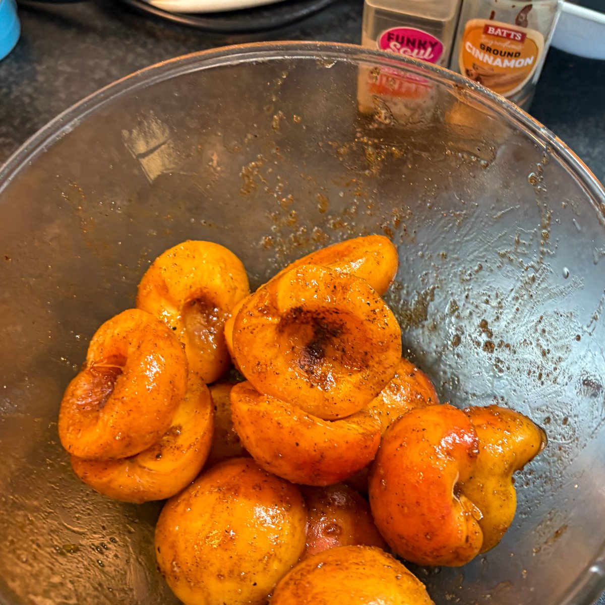 Apricot halves coated in brown sugar, cinnamon and nutmeg, glossy and spiced in a glass bowl