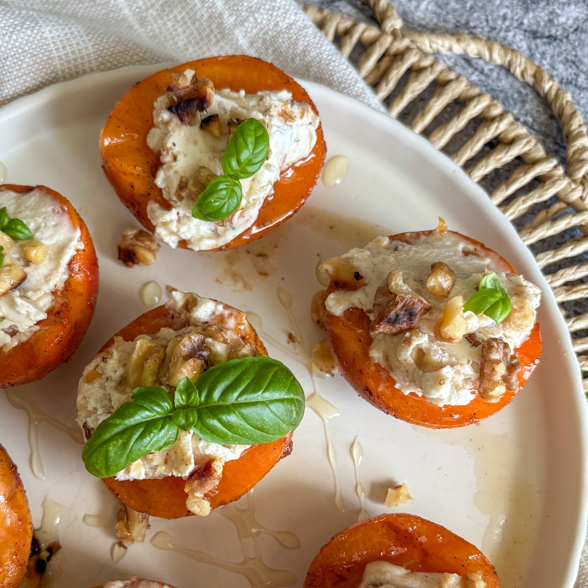 Grilled apricots, soft and honeyed, with smooth mascarpone, crunchy walnuts and fresh basil in close-up