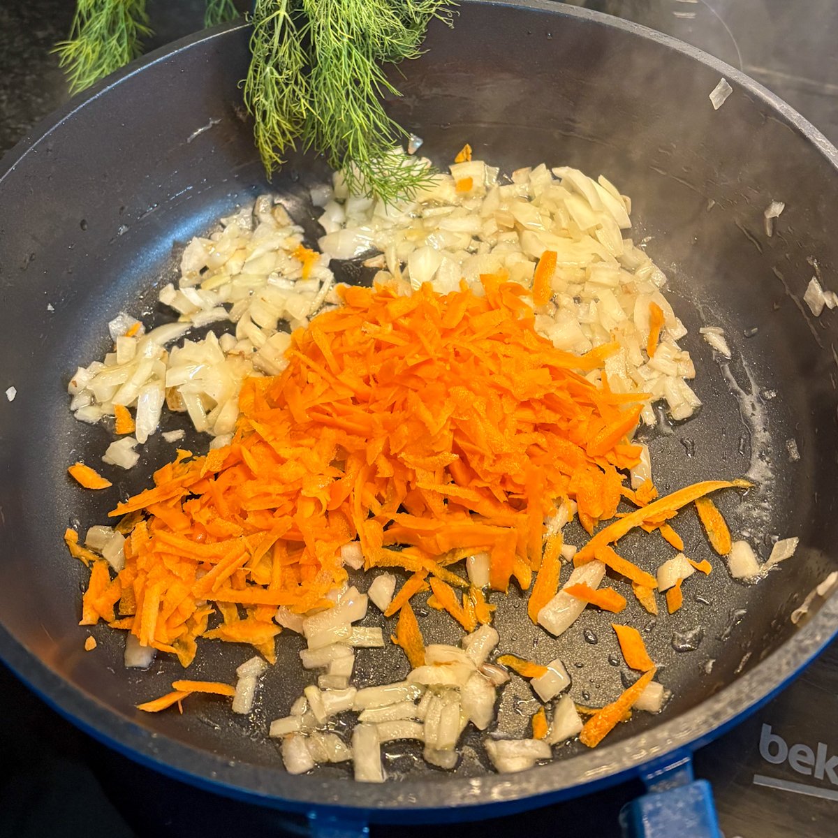 Onion, grated carrot in a pan to start pearl barley with mushrooms