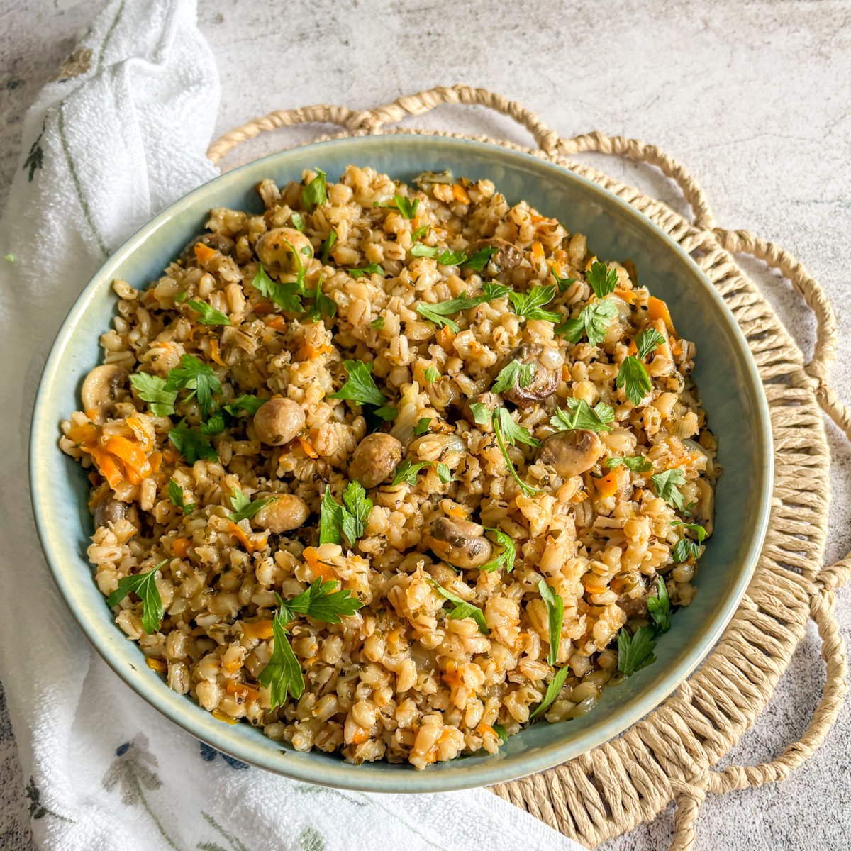 Bowl of easy pearl barley with mushrooms on a white floral cloth