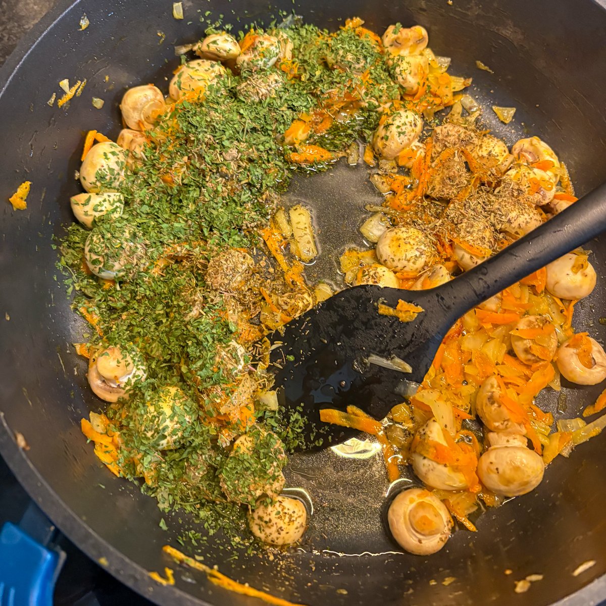 Mushrooms, carrot and herbs sautéed in a pan for pearl barley with mushrooms