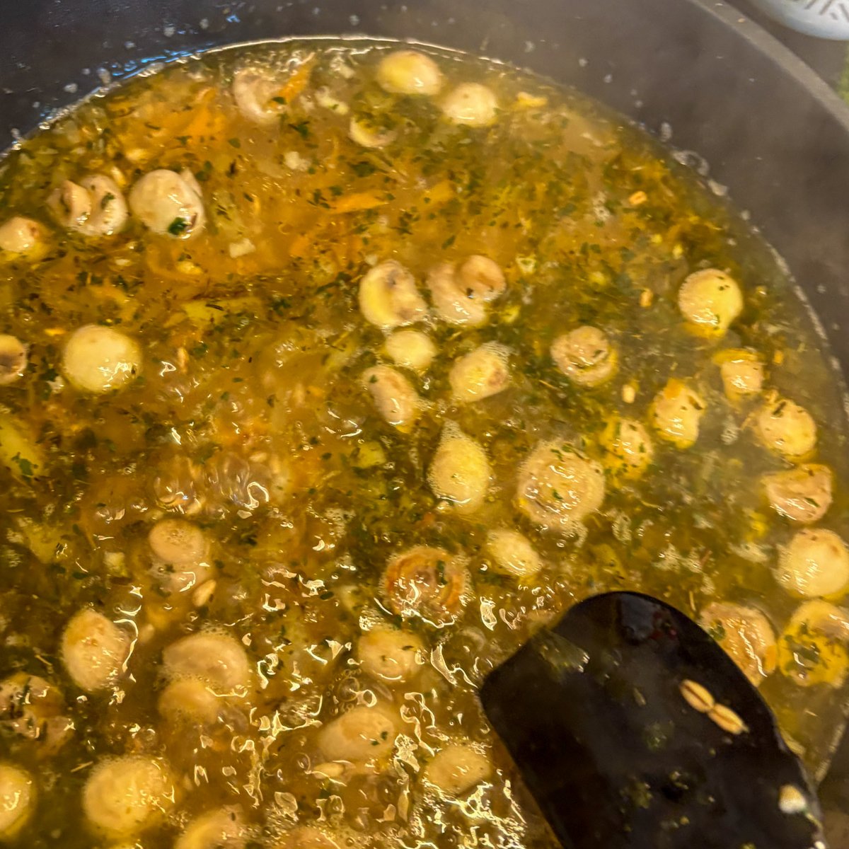 Pearl barley with mushrooms simmering in herby vegetable stock in a pan
