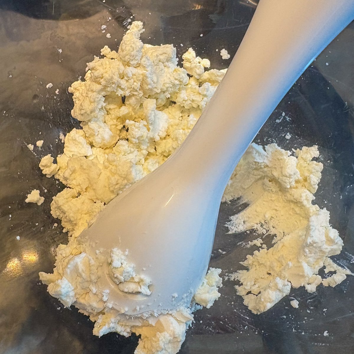 Crumbled block feta in a metal mixing bowl with a hand blender, the first step of making whipped feta dip before the yoghurt and lemon go in.